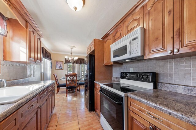 kitchen with sink, an inviting chandelier, tasteful backsplash, white appliances, and light tile patterned flooring