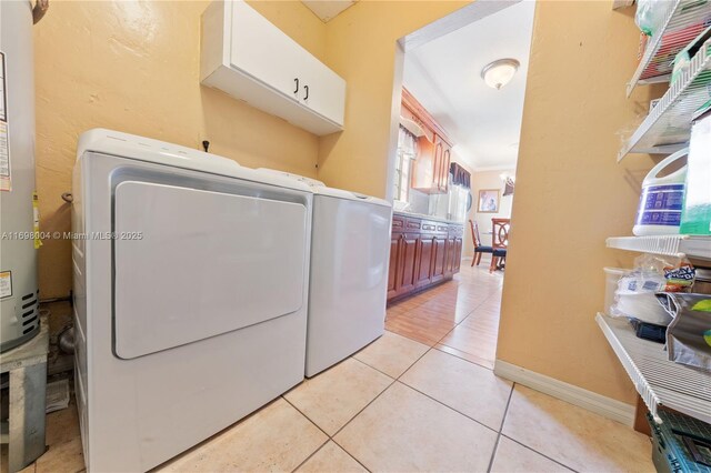 laundry area featuring cabinets, washer and clothes dryer, ornamental molding, and light tile patterned flooring