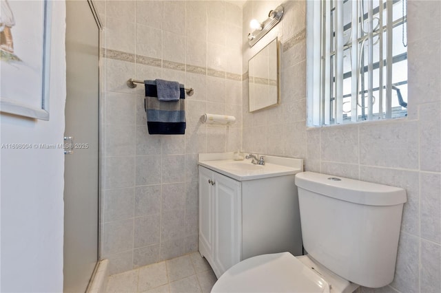 bathroom featuring vanity, tile walls, tile patterned flooring, toilet, and a shower with shower door