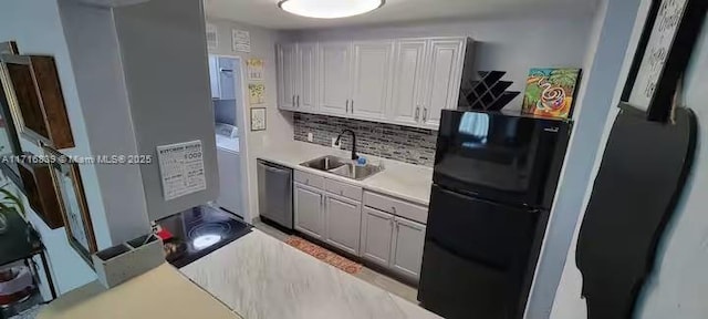 kitchen with white cabinets, black fridge, tasteful backsplash, sink, and dishwasher