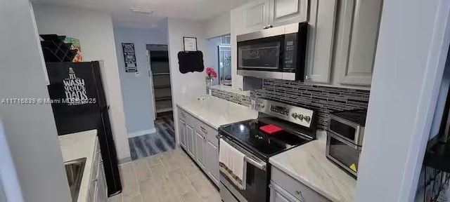 kitchen with appliances with stainless steel finishes, backsplash, gray cabinets, and light hardwood / wood-style floors