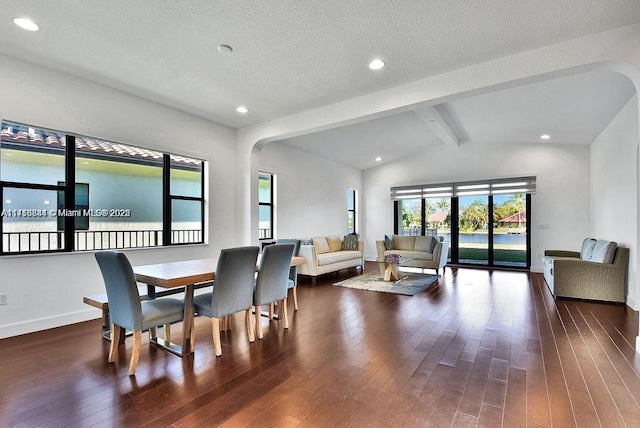 dining area featuring a textured ceiling, lofted ceiling with beams, and dark wood-type flooring