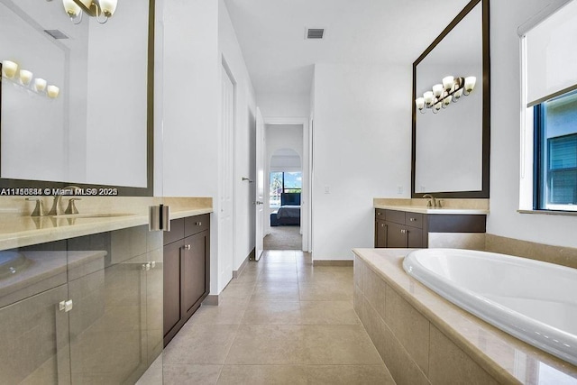 bathroom featuring tile patterned flooring, vanity, and a relaxing tiled tub