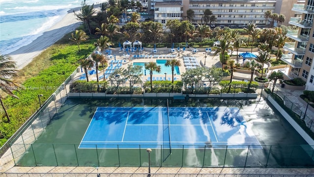 view of tennis court featuring a view of the beach and fence