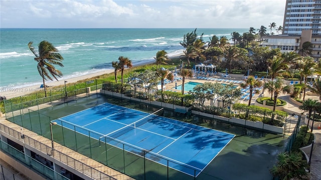 view of sport court featuring a beach view, a water view, and fence