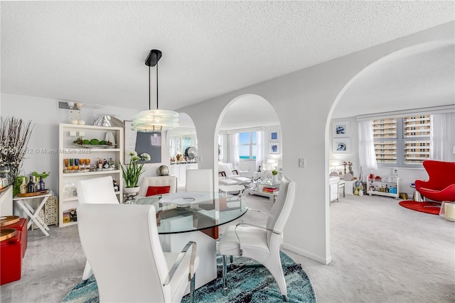 carpeted dining area with visible vents, arched walkways, and a textured ceiling