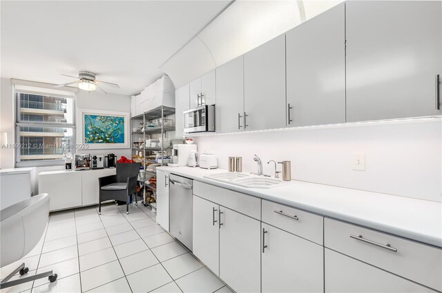 kitchen featuring sink, ceiling fan, light tile patterned floors, appliances with stainless steel finishes, and white cabinetry