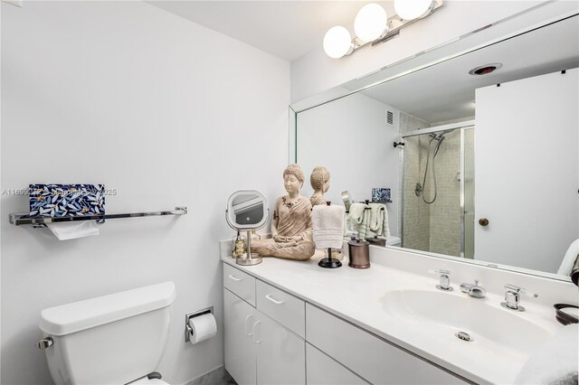 bathroom with toilet, an enclosed shower, and vanity