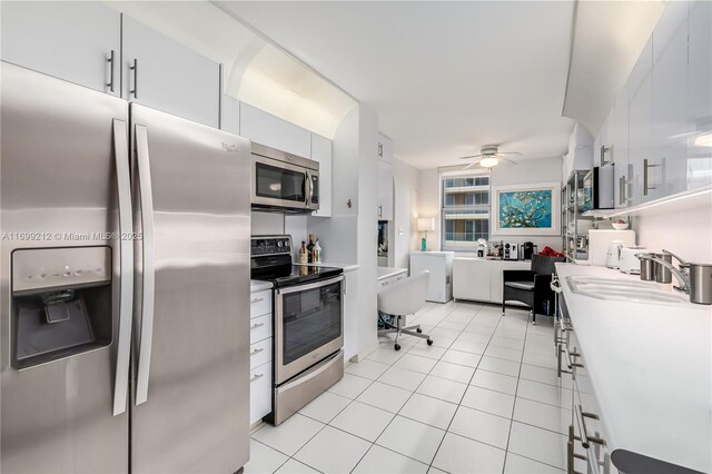 kitchen with appliances with stainless steel finishes, ceiling fan, sink, light tile patterned floors, and white cabinets