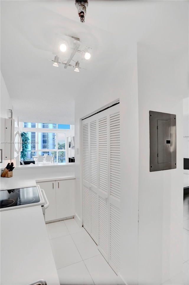 kitchen with white cabinets, range, electric panel, and light tile patterned floors