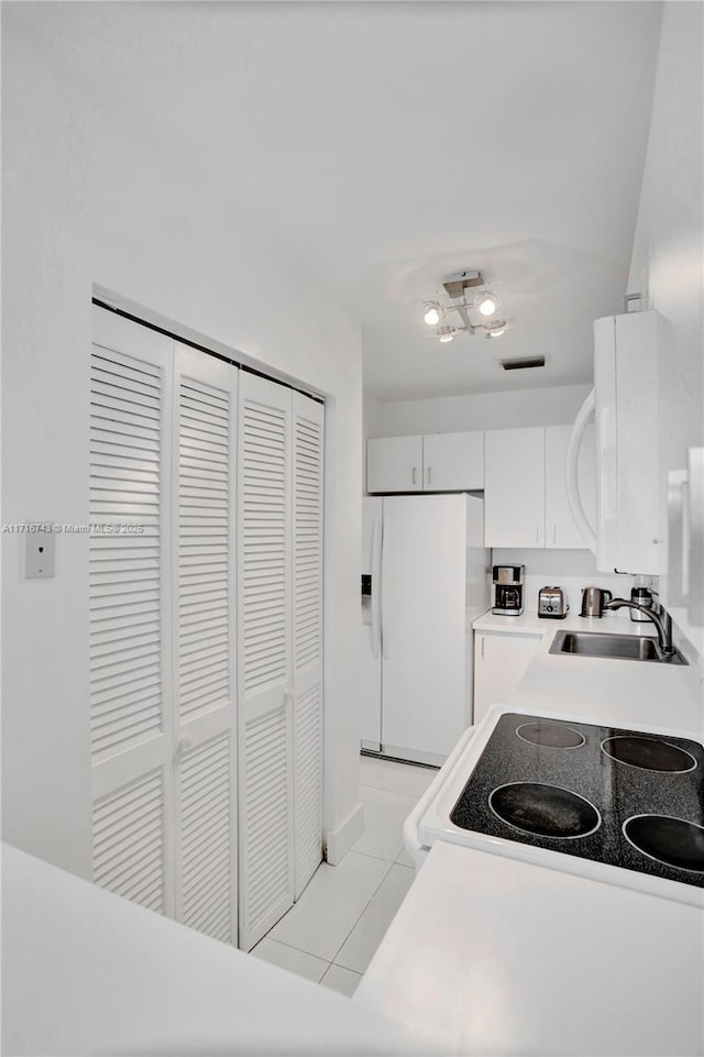 kitchen featuring sink, white cabinets, range, white fridge with ice dispenser, and light tile patterned flooring