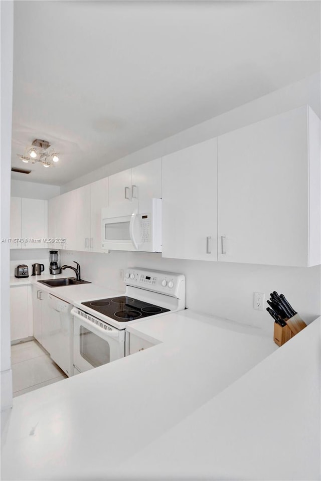 kitchen featuring white appliances, white cabinetry, and sink