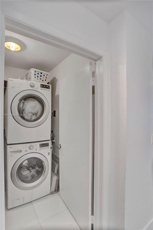 laundry room with tile patterned floors and stacked washer / drying machine