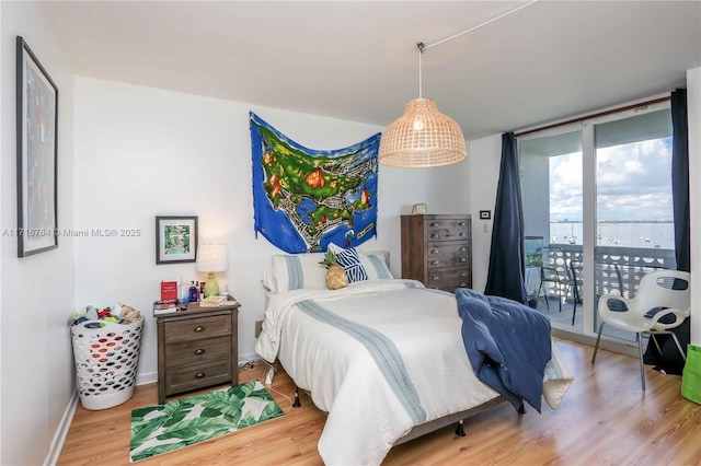 bedroom featuring access to outside, light hardwood / wood-style flooring, and floor to ceiling windows