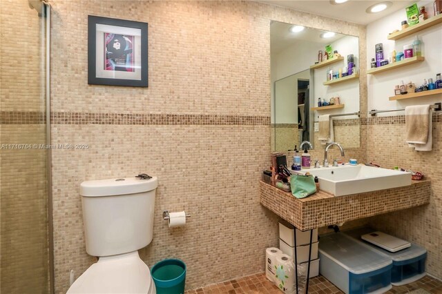 bathroom featuring tile patterned floors, toilet, tile walls, and sink