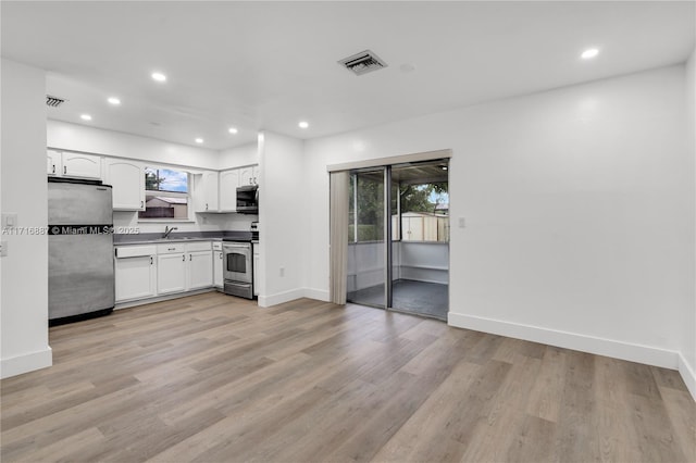 kitchen featuring light wood-type flooring, stainless steel appliances, white cabinetry, and sink