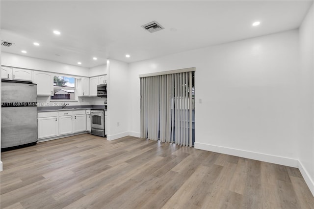 kitchen with light wood-type flooring, stainless steel appliances, white cabinetry, and sink