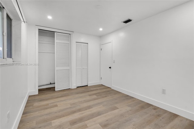 unfurnished bedroom with two closets and light hardwood / wood-style flooring