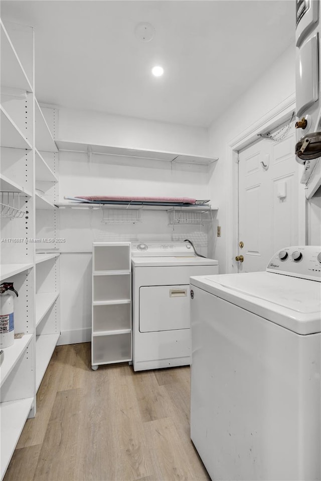 laundry area with separate washer and dryer and light hardwood / wood-style flooring