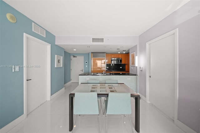 kitchen featuring backsplash, sink, light tile patterned floors, a kitchen bar, and kitchen peninsula