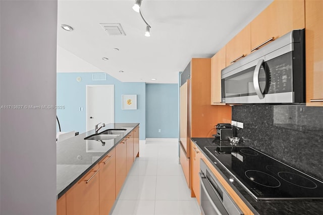 kitchen with wall oven, dark stone counters, cooktop, sink, and light tile patterned flooring