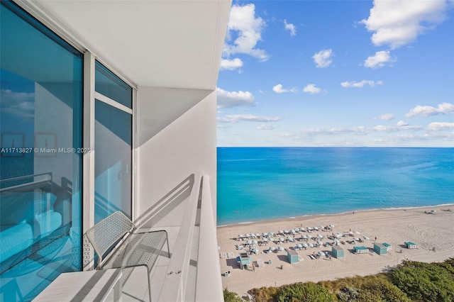 balcony with a water view and a view of the beach