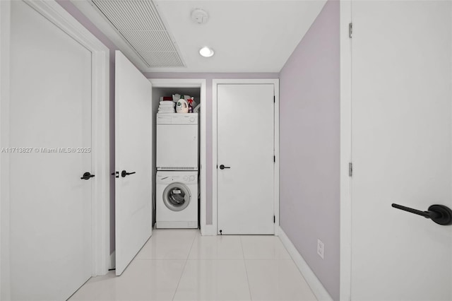 washroom with light tile patterned flooring and stacked washer / drying machine