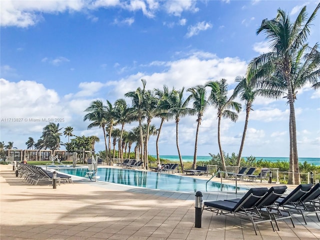 view of swimming pool featuring a water view and a patio area