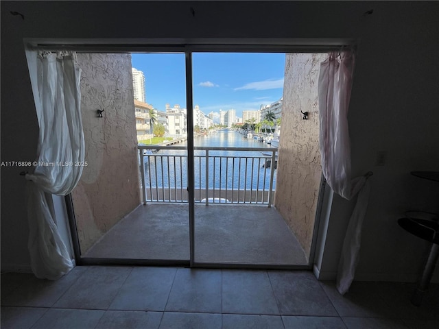 doorway to outside with tile patterned floors and a water view