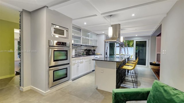 kitchen featuring white cabinetry, built in microwave, double oven, decorative light fixtures, and a kitchen island