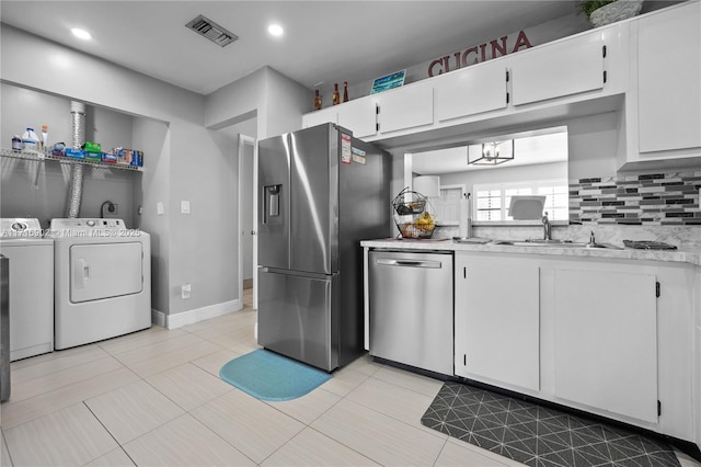 kitchen with washer and dryer, light tile patterned floors, white cabinetry, and appliances with stainless steel finishes