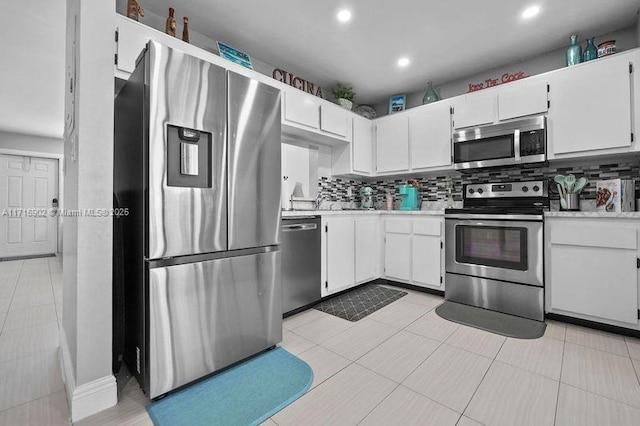 kitchen featuring decorative backsplash, white cabinetry, light tile patterned floors, and appliances with stainless steel finishes