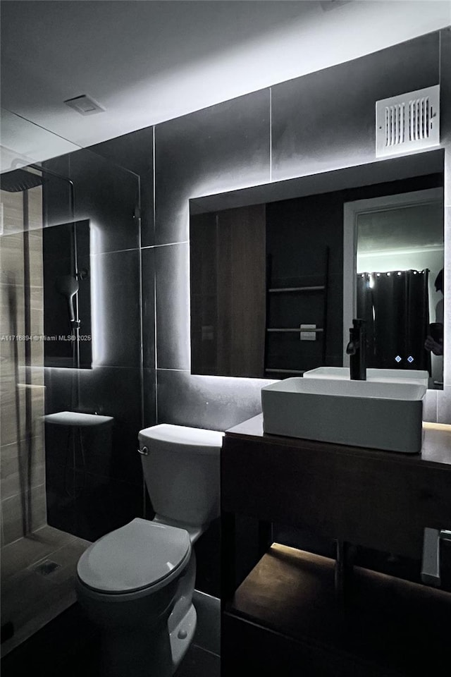 bathroom featuring a shower, vanity, toilet, and tile walls