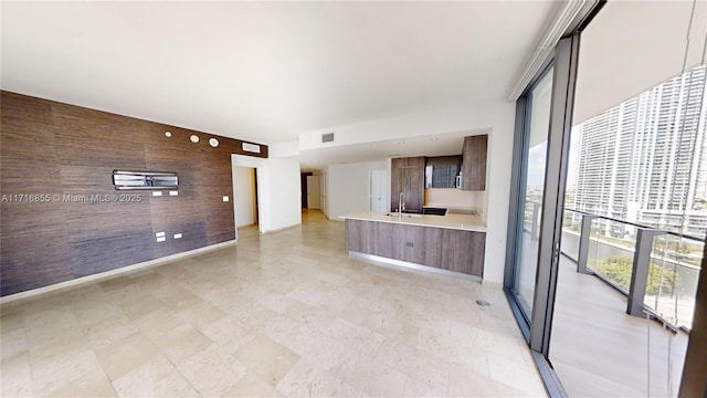 unfurnished living room with floor to ceiling windows, wooden walls, and sink