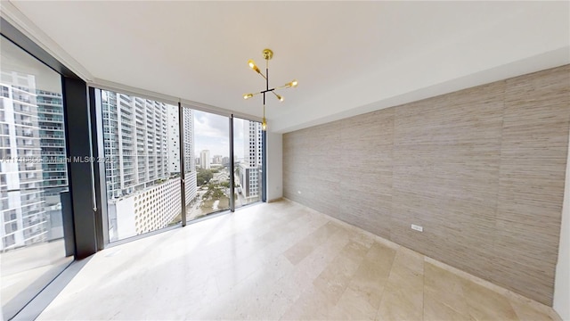 spare room featuring an inviting chandelier and a wall of windows