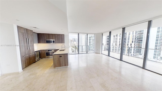 kitchen featuring a kitchen island, sink, beverage cooler, stainless steel appliances, and floor to ceiling windows