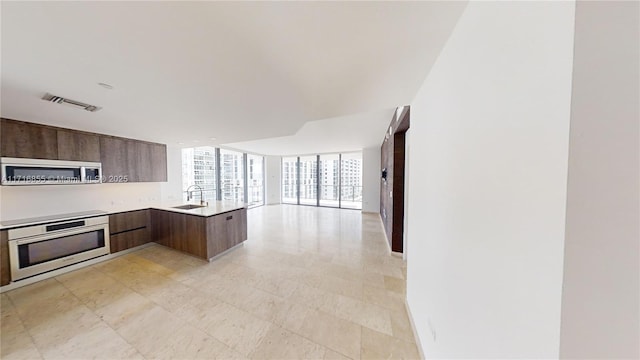 kitchen featuring sink, a wall of windows, wall oven, black electric cooktop, and kitchen peninsula