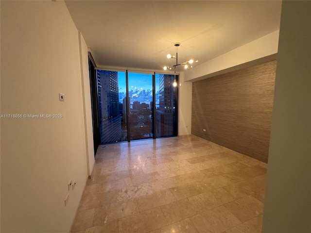 empty room featuring expansive windows and a notable chandelier