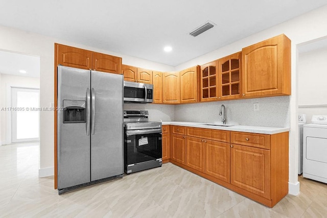 kitchen featuring washer and dryer, decorative backsplash, stainless steel appliances, and sink