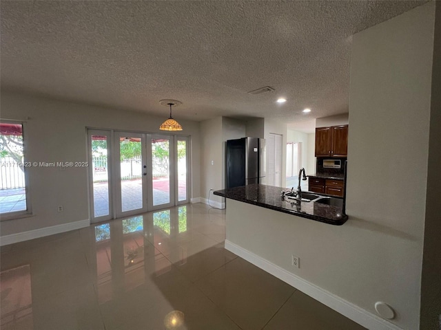 kitchen with stainless steel refrigerator, sink, french doors, hanging light fixtures, and light tile patterned floors