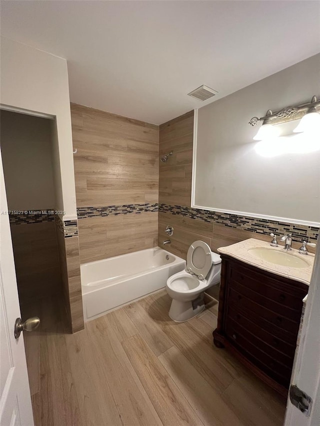 full bathroom featuring hardwood / wood-style floors, vanity, bathing tub / shower combination, toilet, and tile walls