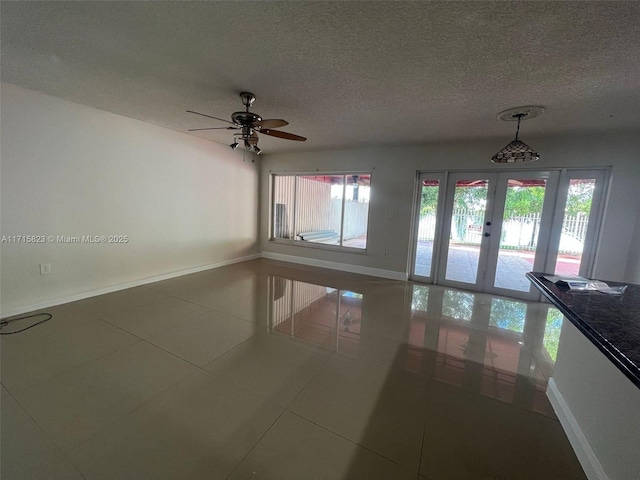 tiled empty room featuring ceiling fan, a textured ceiling, and french doors