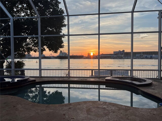 back of property with a water view and glass enclosure