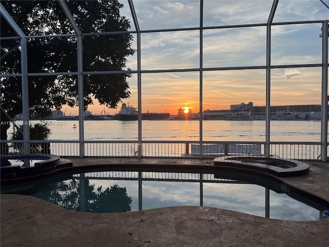 pool at dusk featuring a water view