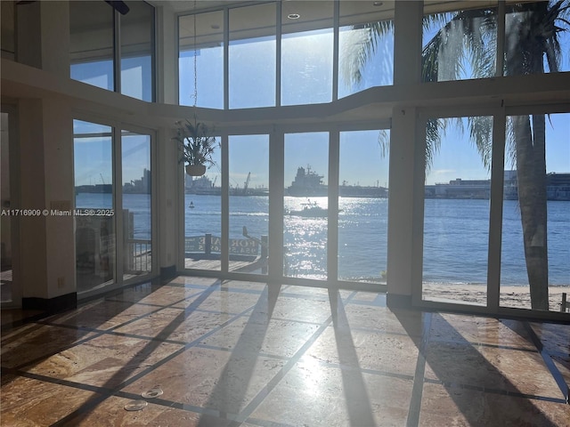 unfurnished sunroom featuring a water view