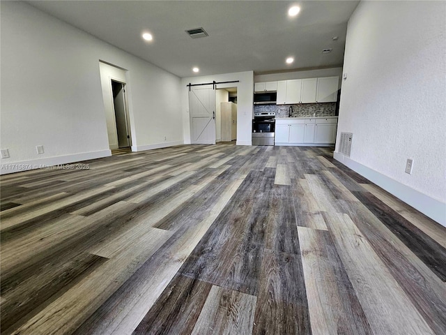 unfurnished living room with a barn door and wood-type flooring