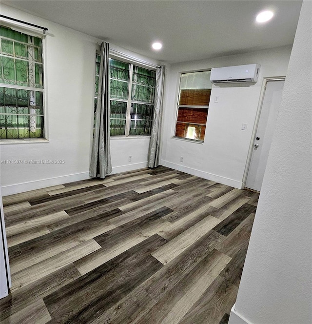 unfurnished room featuring a wall mounted AC and dark wood-type flooring