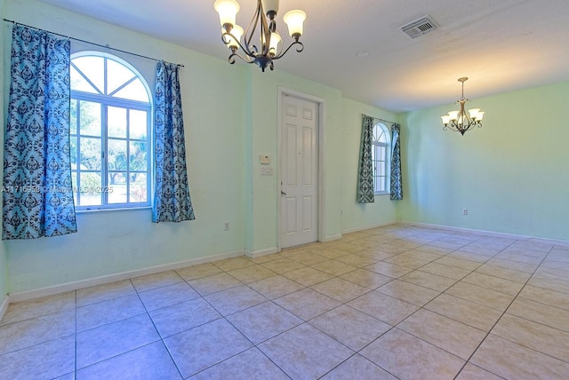 spare room featuring light tile patterned flooring and a chandelier