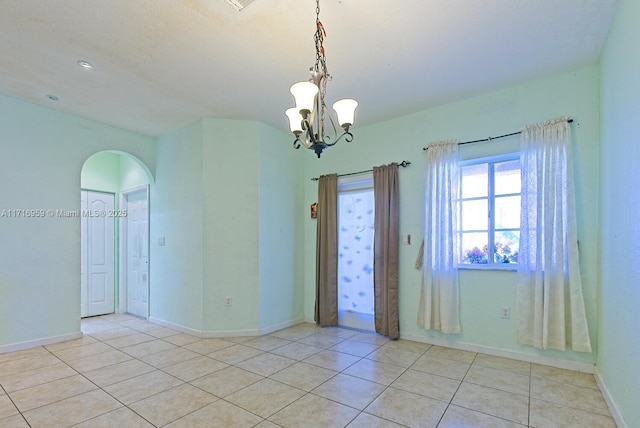 tiled spare room with a chandelier