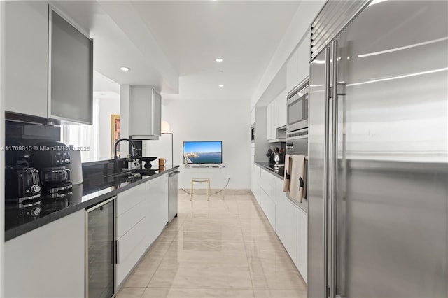 kitchen featuring white cabinetry, sink, wine cooler, built in appliances, and light tile patterned floors